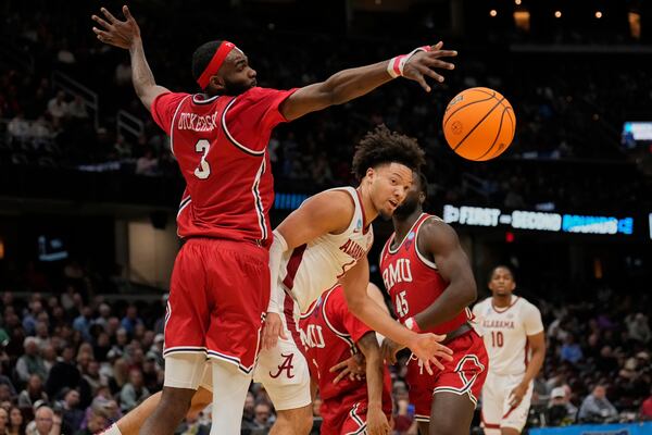 Alabama guard Mark Sears, center, passes in front of Robert Morris guard Amarion Dickerson (3) in the first half in the first round of the NCAA college basketball tournament, Friday, March 21, 2025, in Cleveland. (AP Photo/Sue Ogrocki)