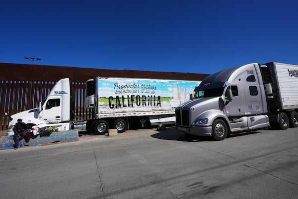 Trucks line up to cross the border into the United States as tariffs against Mexico go into effect, Tuesday, March 4, 2025, in Tijuana, Mexico. (AP Photo/Gregory Bull)