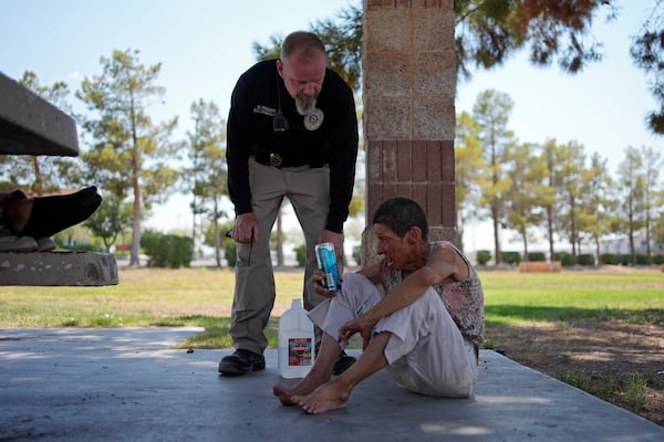 FILE - Mark Paulson, a Public Response and Code Enforcement officer, checks on Deb Billet, 66, before calling an ambulance to take her to a hospital for heat-related symptoms July 10, 2024, in Henderson, Nev. (AP Photo/John Locher, File)