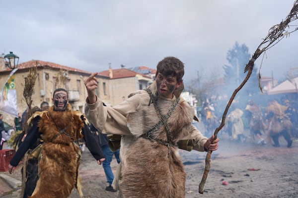 A boy dressed in animal skins and heavy bronze bells, gestures during carnival celebrations in Distomo, a village in central Greece, on Monday, March 3, 2025. (AP Photo/Petros Giannakouris)