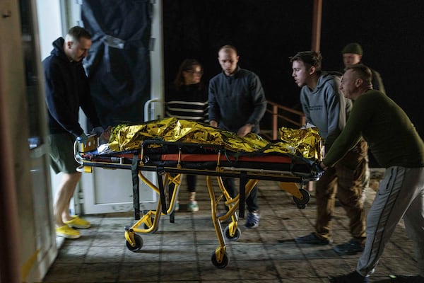 Medics haul an injured Ukrainian serviceman on a stretcher from an ambulance at Medical Service "Ulf" of the 108th Separate Battalion "Da Vinci Wolves" on Pokrovsk direction, Ukraine, Tuesday, Dec. 24, 2024. (AP Photo/Evgeniy Maloletka)