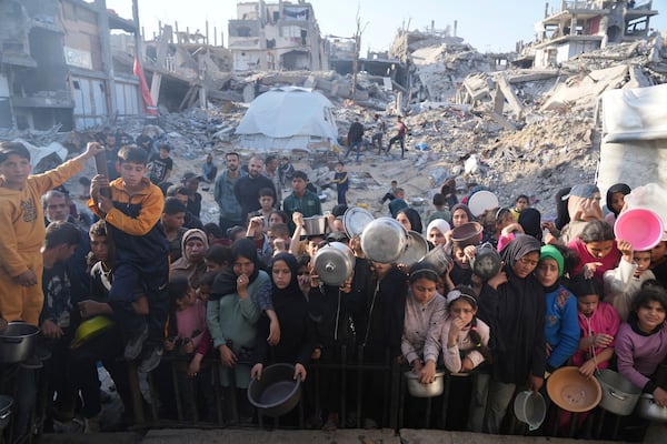 Palestinian wait get donated food at a distribution center in Beit Lahiya, northern Gaza Strip, Sunday, March 16, 2025. (AP Photo/Abdel Kareem Hana)