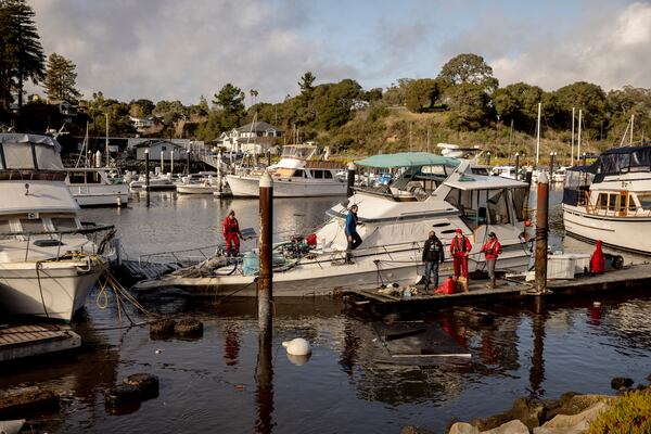 Recovery crews pump water from a semi-submerged boat in Santa Cruz Harbor after it was damaged during high surf in Santa Cruz, Calif., Tuesday, Dec. 24, 2024. (Santa Cruz/San Francisco Chronicle via AP)