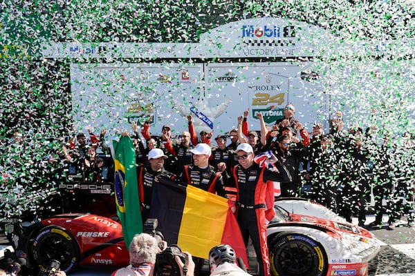 Porsche Penske Motorsport team drivers, from left to right, Brazil's Felipe Nasr, Belgium's Laurens Vanthoor and Britain's Nick Tandy celebrate in Victory Lane after winning the IMSA Rolex 24 hour auto race at Daytona International Speedway, Sunday, Jan. 26, 2025, in Daytona Beach, Fla. (AP Photo/John Raoux)