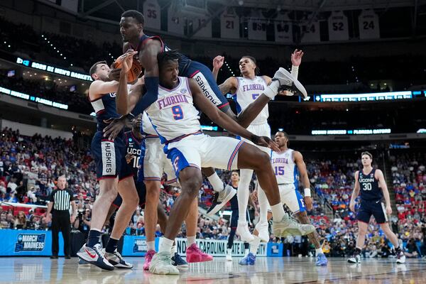 UConn center Samson Johnson falls over Florida center Rueben Chinyelu during the first half in the second round of the NCAA college basketball tournament, Sunday, March 23, 2025, in Raleigh, N.C. (AP Photo/Chris Carlson)