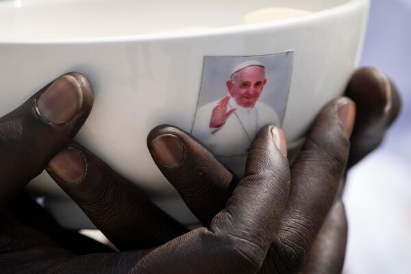 FILE - A priest holds a sacrament bowl showing a photograph of Pope Francis during a Holy Mass at the John Garang Mausoleum in Juba, South Sudan, Feb. 5, 2023. (AP Photo/Ben Curtis, File)