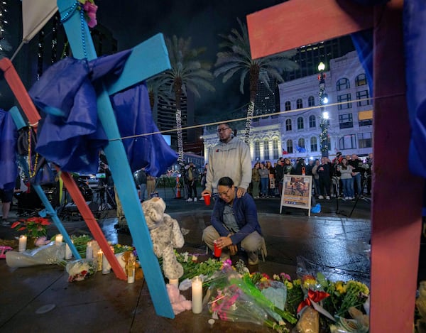 Mourners react next to crosses memorializing the victims of the New Year's Day deadly truck attack and shooting along Canal Street near the intersection of Bourbon Street in New Orleans, Saturday, Jan. 4, 2025. (AP Photo/Matthew Hinton)