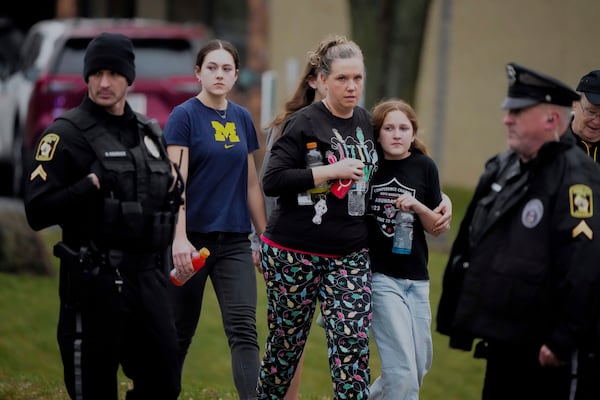 A family leave the shelter after multiple injuries were reported following a shooting at the Abundant Life Christian School, Monday, Dec. 16, 2024. (AP Photo/Morry Gash)