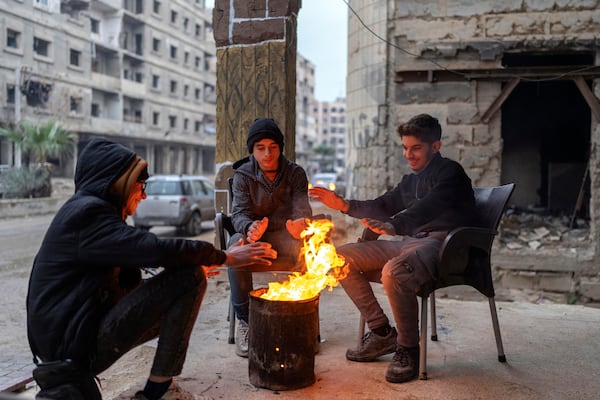 Boys warm up next to a fire on a cold day in Douma, on the outskirts of Damascus, Syria, Sunday, Dec. 29, 2024 (AP Photo/Mosa'ab Elshamy)