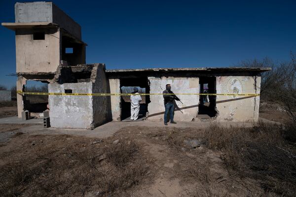 FILE - A forensic technician, guarded by a National Guardsman, stands inside a ruined house where bodies were ripped apart and incinerated, on a plot of land referred to as a cartel "extermination site", on the outskirts of Nuevo Laredo, Mexico, Feb. 8, 2022. (AP Photo/Marco Ugarte, File)