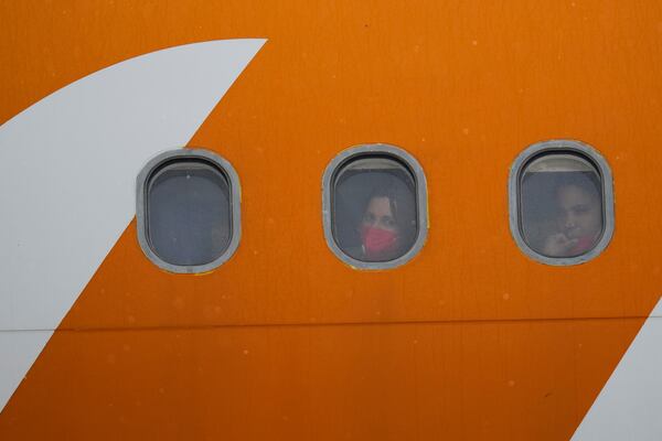 Venezuelan migrants deported from the United States look out from plane portholes upon landing at the Simon Bolivar International Airport in Maiquetia, Venezuela, Friday, May 2, 2025. (AP Photo/Ariana Cubillos)