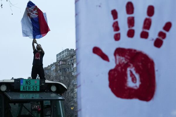 A man holds a Serbian flag during a protest, day after the assault on students was carried out by thugs with baseball bats, in Novi Sad, Serbia, Tuesday, Jan. 28, 2025. (AP Photo/Darko Vojinovic)