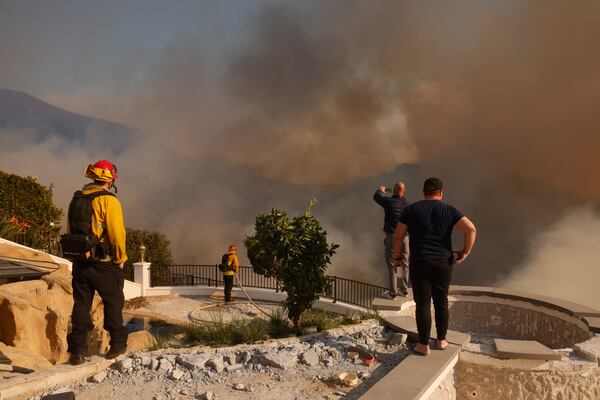 Residents and firefighters watch as the Palisades Fire advances in the Pacific Palisades neighborhood of Los Angeles Tuesday, Jan. 7, 2025. (AP Photo/Etienne Laurent)