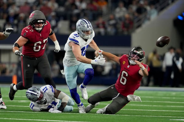 Dallas Cowboys linebacker Micah Parsons (11) strips the ball away from Tampa Bay Buccaneers quarterback Baker Mayfield (6) as Nick Vigil (41) attempts to recover the ball that fell out-of-bounds in the second half of an NFL football game in Arlington, Texas, Sunday, Dec. 22, 2024. (AP Photo/Jeffrey McWhorter)