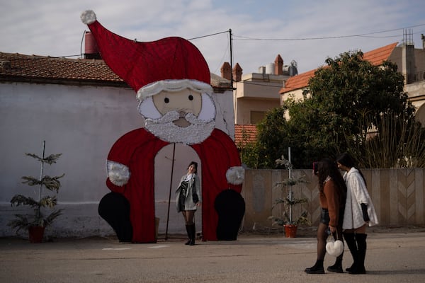 A young woman poses for a picture with a Christmas decoration on a square in a Christian neighbourhood, in Homs, Syria, Thursday, Dec. 26, 2024. (AP Photo/Leo Correa)