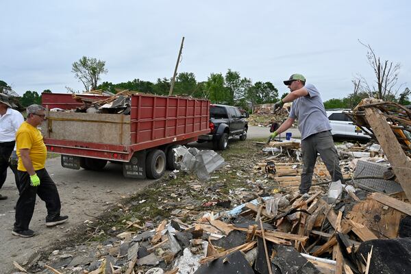 Volunteers load a dump truck with debris during cleanup efforts after severe storms in the Sunshine Hills neighborhood in London, Ky., Monday, May 19, 2025. (AP Photo/Timothy D. Easley)