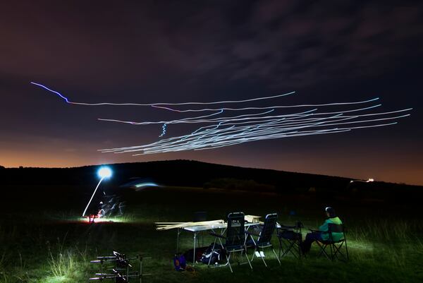 This handout photo taken with long exposure shows a researcher of the Eötvös Loránd University observing the flight of a flock of autonomous drones during an experiment near Budapest, Hungary, Thursday, Oct. 21, 2021. (AP Photo/HO/Eotvos Lorand University)