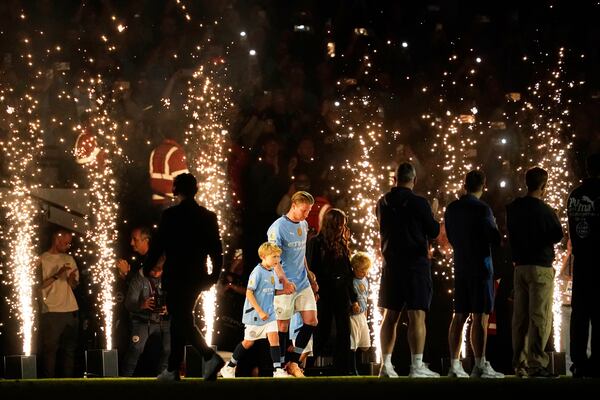 Manchester City's Kevin De Bruyne accompanied by his family walks on the pitch after his final home game during the English Premier League soccer match between Manchester City and Bournemouth at the Etihad stadium in Manchester, England, Tuesday, May 20, 2025. (AP Photo/Dave Thompson)