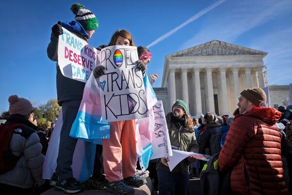 FILE - Children hold signs and transgender pride flags as supporters of transgender rights rally by the Supreme Court, Dec. 4, 2024, in Washington. (AP Photo/Jacquelyn Martin, File)