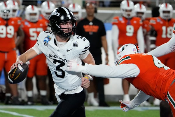 Iowa State quarterback Rocco Becht (3) escapes a sack from Miami defensive lineman Rueben Bain Jr., right, during the second half of the Pop Tarts Bowl NCAA college football game, Saturday, Dec. 28, 2024, in Orlando, Fla. (AP Photo/John Raoux)