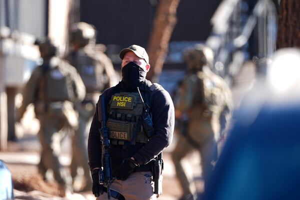 Law officials move through an apartment complex during a raid Wednesday, Feb. 5, 2025, in east Denver. (AP Photo/David Zalubowski)