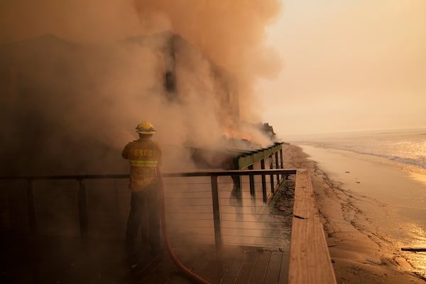 A firefighter protects a beach front property while fighting the Palisades Fire Thursday, Jan. 9, 2025 in Malibu, Calif. (AP Photo/Jae C. Hong)