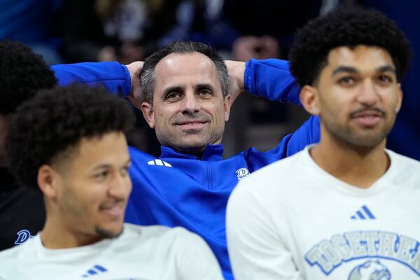 Drake head coach Ben McCollum, center, reacts while watching the broadcast of the NCAA college men's basketball tournament selection show, Sunday, March 16, 2025, in Des Moines, Iowa. (AP Photo/Charlie Neibergall)