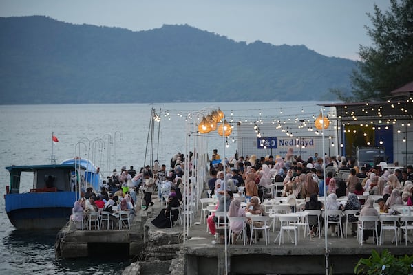 People sit at a coffee shop on the waterfront near Ulee Lheue beach that was one of the areas hardest hit by Indian Ocean tsunami in 2004, in Banda Aceh, Aceh Province, Indonesia, Saturday, Dec. 14, 2024. (AP Photo/Achmad Ibrahim)