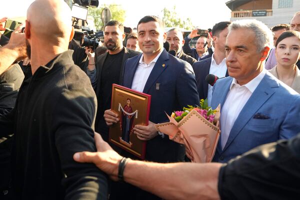 Presidential candidate George Simion, left, holds a religious icon as he walks with Calin Georgescu, winner of the first round of last year's annulled election, after casting his vote in the first round of the presidential election redo in Mogosoaia, Romania, Sunday, May 4, 2025. (AP Photo/Vadim Ghirda)