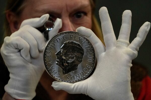 A warden looks through a magnifyer to check a 500 Pound coin during the "Trial of the Pyx,'' a ceremony that dates to the 12th Century in which coins are weighed in order to make certain they are up to standard, at the Goldsmiths' Hall in London, Tuesday, Feb. 11, 2025.(AP Photo/Frank Augstein)