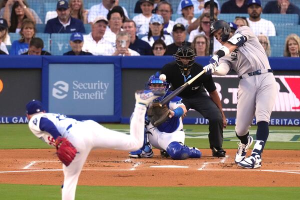 New York Yankees' Aaron Judge, right, hits a solo home run as Los Angeles Dodgers starting pitcher Tony Gonsolin, left, and catcher Will Smith watch during the first inning of a baseball game Friday, May 30, 2025, in Los Angeles. (AP Photo/Mark J. Terrill)