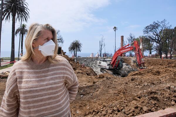 Pacific Palisades property owner DeAnn Heline stands in front of her home being rebuilt after the Palisades Fire in the Pacific Palisades section of Los Angeles, Thursday, April 24, 2025. (AP Photo/Damian Dovarganes)