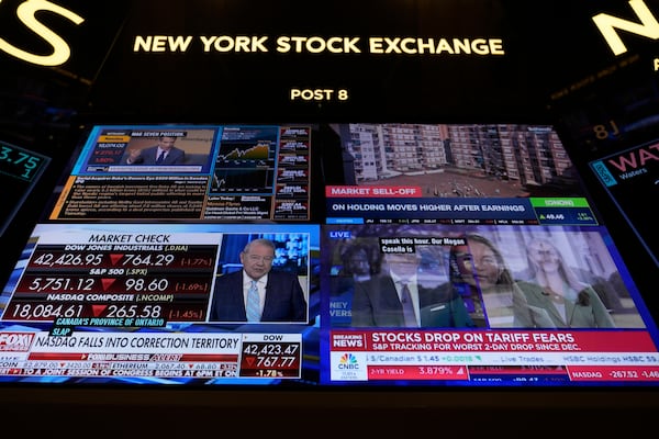 Financial news is displayed as people work on the floor at the New York Stock Exchange in New York, Tuesday, March 4, 2025. (AP Photo/Seth Wenig)