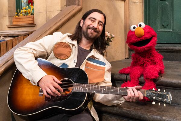 This image released by Sesame Workshop shows singer Noah Kahan, left, with muppet character Elmo on the set of "Sesame Street." (Zach Hyman/Sesame Workshop via AP)