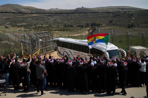 Buses carrying members of the Syrian Druze community are welcomed by Druze clerics at the border with Syria, as they enter into the village of Majdal Shams, in the Israeli-controlled Golan Heights, Friday, March 14, 2025. (AP Photo/Leo Correa)