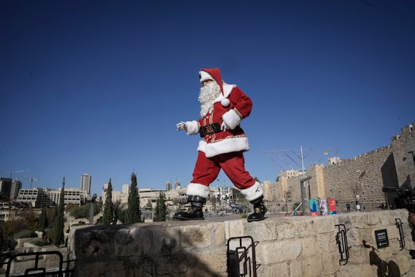 dressed as Santa Claus, walks along a wall next to the Old City of Jerusalem, ahead of the Christmas holiday, Thursday, Dec. 19, 2024.(AP Photo/Mahmoud Illean)