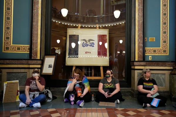 Protesters sit in the rotunda at the Iowa state Capitol to denounce a bill that would strip the state civil rights code of protections based on gender identity, Thursday, Feb. 27, 2025, in Des Moines, Iowa. (AP Photo/Charlie Neibergall)