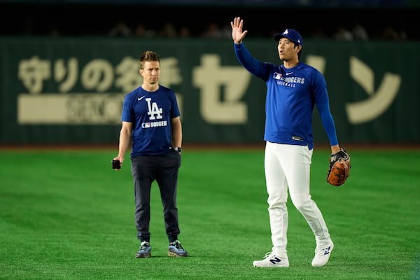 Los Angeles Dodgers' Shohei Ohtani waves from the field as he warms up before a spring training baseball game against the Yomiuri Giants in Tokyo, Japan, Saturday, March 15, 2025. (AP Photo/Eugene Hoshiko)