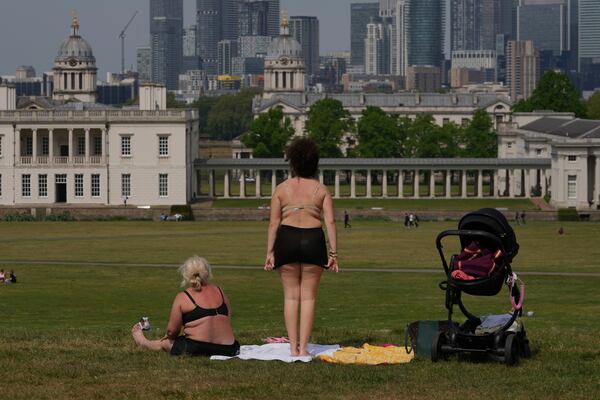 People sunbathe on a sunny day at a park in London, Thursday, May 1, 2025. (AP Photo/Kin Cheung)