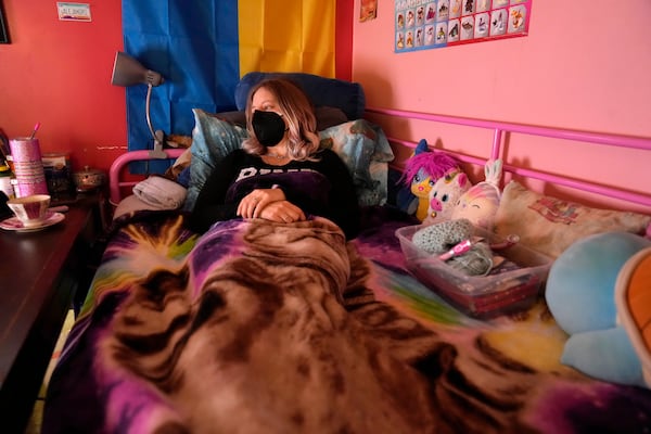 Ashley Alejandro watches television in a bed in the basement of her home where she spends most of her time due to chronic illness Wednesday, Dec. 18, 2024, in Wentzville, Mo. (AP Photo/Jeff Roberson)