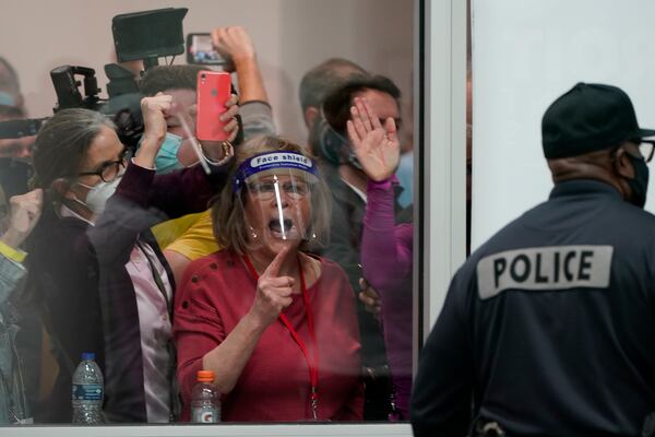 FILE - Election challengers yell as they look through the windows of the central counting board as police were helping to keep additional challengers from entering due to overcrowding, Nov. 4, 2020, in Detroit. (AP Photo/Carlos Osorio, File)