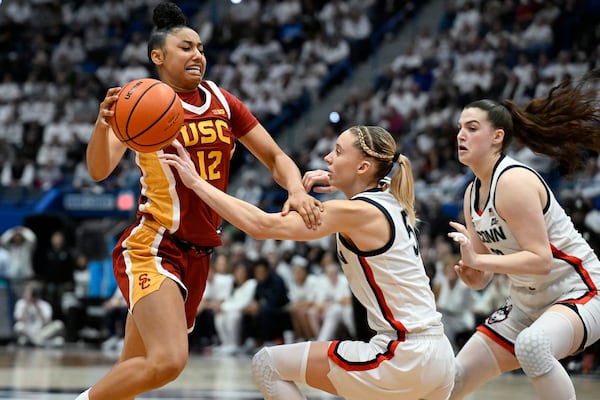 Southern California guard JuJu Watkins, left, drives to the basket as UConn guards Paige Bueckers, center, and Morgan Cheli, right, defend in the second half of an NCAA college basketball game, Saturday, Dec. 21, 2024, in Hartford, Conn. (AP Photo/Jessica Hill)