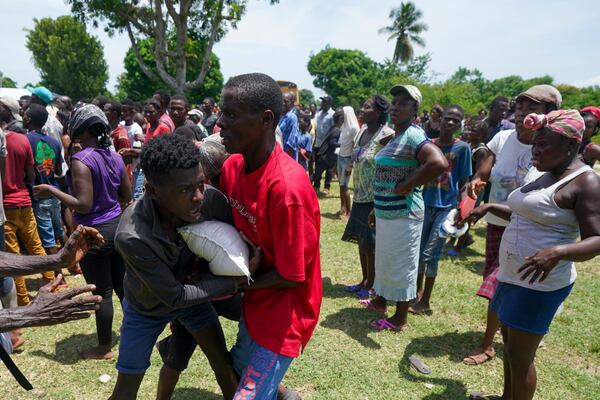 FILE - Men scuffle over a sack of donated food taken from a truck loaded with relief supplies, in Vye Terre, Haiti, Aug. 20, 2021. Private aid and shipments from the U.S. government and others were arriving in the country's southwestern peninsula that was struck by a 7.2 magnitude quake on Aug. 14. (AP Photo/Fernando Llano, File)