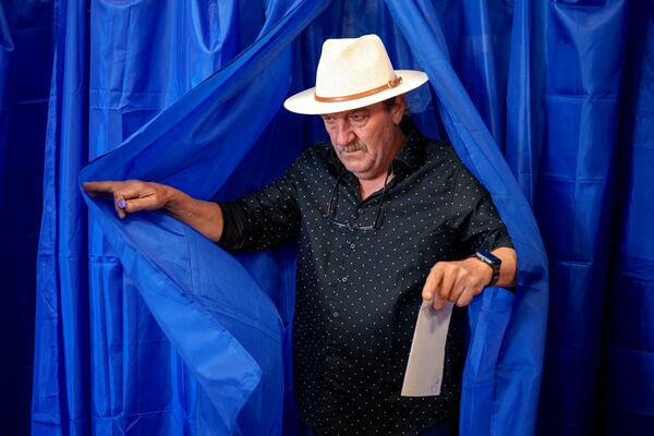 A man exits a voting booth before casting his vote in the first round of the presidential election redo in Bucharest, Romania, Sunday, May 4, 2025. (AP Photo/Andreea Alexandru)