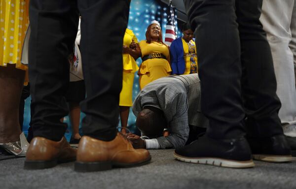 Rev. Reginald Silencieux kneels to pray, surrounded by the choir and worship team at the First Haitian Evangelical Church of Springfield, Sunday, January 26, 2025, in Springfield, Ohio. (AP Photo/Jessie Wardarski)