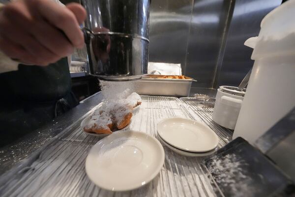 Powdered sugar is sifted onto beignets in Cafe du Monde in City Park in New Orleans, Friday, Jan. 24, 2025. (AP Photo/Gerald Herbert)