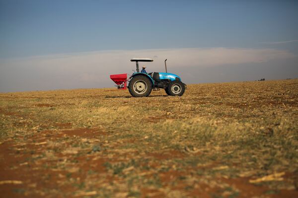 FILE- A farm hand spreads fertilizer on John Rankin's commercial farm in Gerdau, South Africa, Nov. 19, 2018. (AP Photo/Jerome Delay, File)