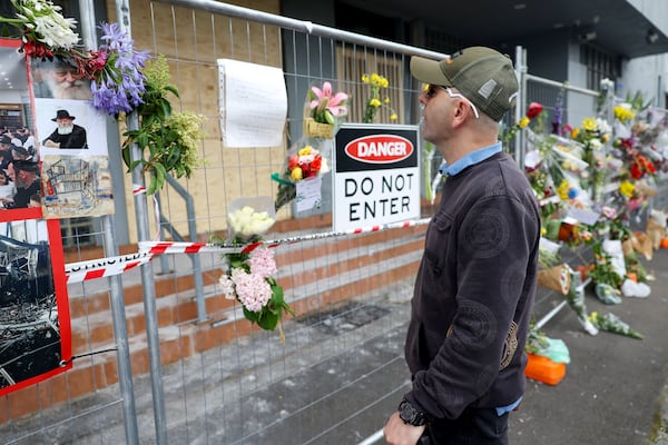 A man reads messages left on the fence outside the fire damaged Adass Israel Synagogue in Melbourne, Monday, Dec. 9, 2024. (Con Chronis/AAP Image via AP)