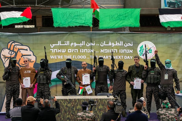 Israeli captives, from left to the right, Ohad Ben Ami, Eli Sharabi and Or Levy, who have been held hostage by Hamas in Gaza since October 7, 2023, are escorted by Hamas fighters before being handed over to the Red Cross in Deir al-Balah, central Gaza Strip, Saturday Feb. 8, 2025. (AP Photo/Abdel Kareem Hana)