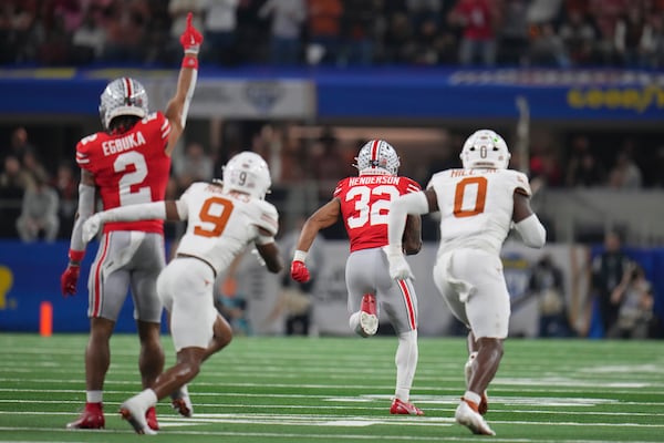 Ohio State wide receiver Emeka Egbuka (2) reacts as running back TreVeyon Henderson (32) runs past Texas defensive back Gavin Holmes (9) and linebacker Anthony Hill Jr. (0) to score during the first half of the Cotton Bowl College Football Playoff semifinal game, Friday, Jan. 10, 2025, in Arlington, Texas. (AP Photo/Julio Cortez)